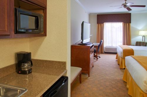 a hotel room with a bed and a room with a television at Holiday Inn Express Hotel & Suites Lufkin South by IHG in Lufkin