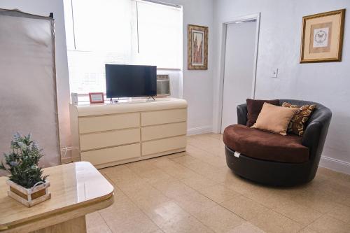 uma sala de estar com uma cadeira e uma televisão em Gallo Condo 33/downtown/8st em Miami