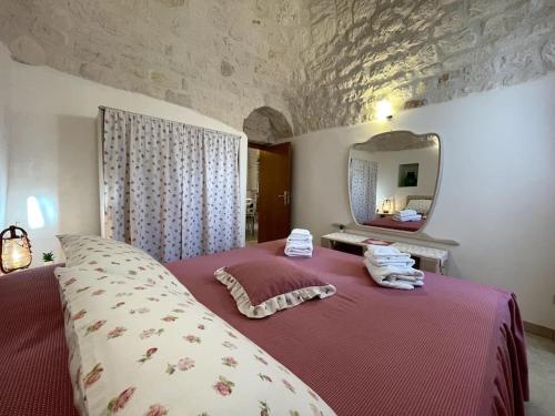 Schlafzimmer mit einem roten Bett und einem Spiegel in der Unterkunft VALLE D'ITRIA Trullo Sovrano sul Monte in Cisternino