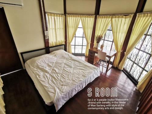 Schlafzimmer mit einem Bett, einem Tisch und Fenstern in der Unterkunft ATOM Poshtel in Mae Sariang