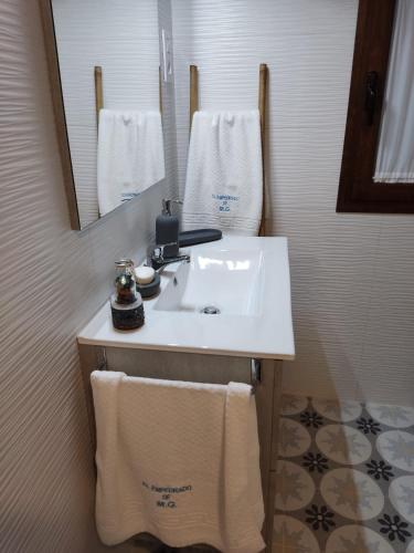 a bathroom with a sink and a mirror and towels at Apartamento Turístico El Empedrado de M&G in Colmenar de Oreja