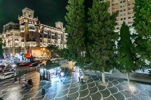 una strada cittadina con un edificio e alberi di notte di M Estate. 2 Room Home in Targovu a Baku