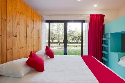 a bedroom with a large bed with red pillows at Capital O Hacienda Filadelfia, El Atorón, Irapuato in Irapuato