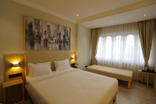 a bedroom with a large white bed and a window at Hotel City Express By Downtown in Udaipur