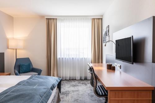 a hotel room with a bed and a desk and a tv at Select Hotel Rüsselsheim in Rüsselsheim