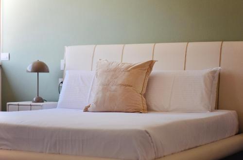 a bed with white sheets and a pillow on it at Torbole Aparthotel in Nago-Torbole