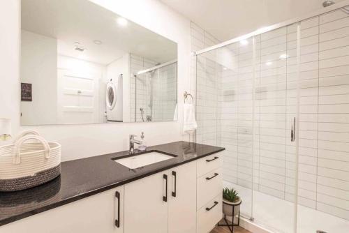 a white bathroom with a sink and a shower at Le coeur du Festival d'été de Québec in Quebec City