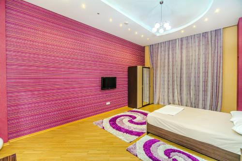 Un dormitorio con una pared rosa con una cama y una alfombra en NIzami Street 4 Room DeLuxe en Baku