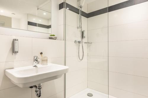 a white bathroom with a sink and a shower at Select Hotel Mainz in Mainz
