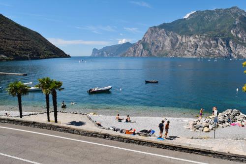 eine Gruppe von Menschen am Strand im Wasser in der Unterkunft Torbole Aparthotel in Nago-Torbole