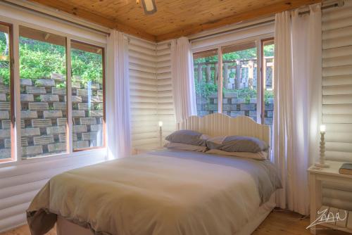 een slaapkamer met een bed in een kamer met ramen bij No10@Kamma in Eersterivierstrand