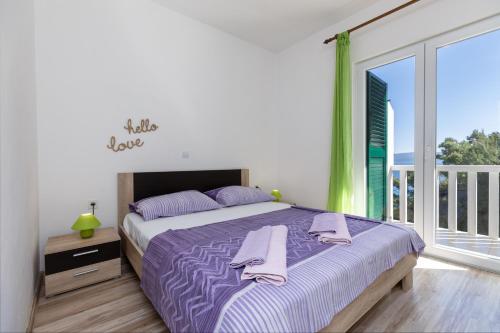 sypialnia z łóżkiem z fioletową pościelą i balkonem w obiekcie Apartments by the sea Mimice, Omis - 2736 w Mimicach