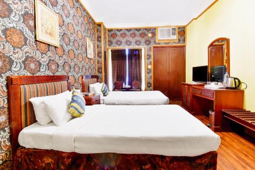 a hotel room with two beds and a television at Capital O 125 Moon Plaza Hotel in Manama