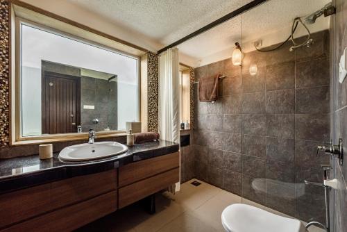 y baño con lavabo y espejo. en SaffronStays Boulevard LogHouse - a wooden chalet amidst nature, en Kārli