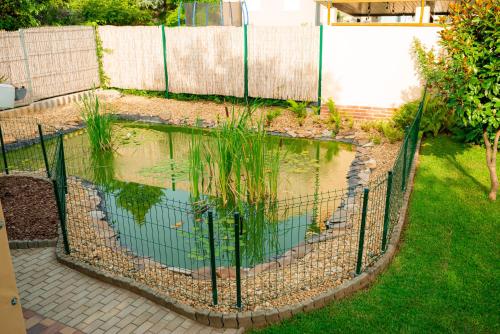 a pond in a fence with plants in it at Bor, Villa, Sóstó in Nyíregyháza