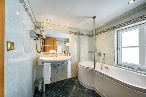 a bathroom with a tub and a sink and a bath tub at Hotel Tannbergerhof im Zentrum von Lech in Lech am Arlberg