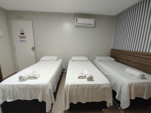 two beds in a hospital room with white sheets at Hotel Universal in Santarém