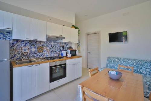 a kitchen with white cabinets and a table with a bowl on it at I giardini dell'Olimpo in Paestum
