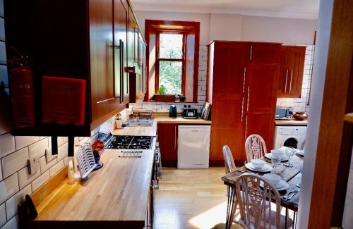 uma cozinha com armários vermelhos e uma mesa com cadeiras em Lovely 2 Bedroom with Riverside Views Pet Friendly em Gourock