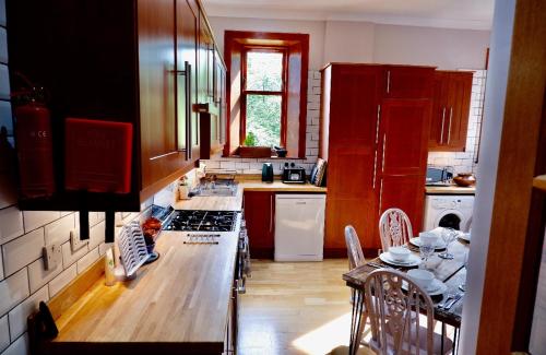 a kitchen with red cabinets and a table with chairs at Lovely 2 Bedroom with Riverside Views Pet Friendly in Gourock