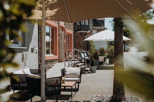 a group of chairs and an umbrella on a patio at Hotel Restaurant zur Marienburg in Pünderich