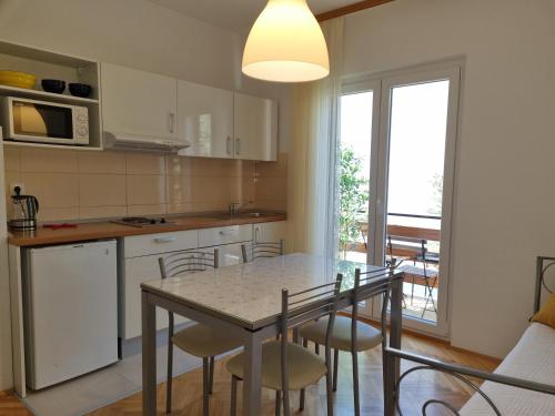 a kitchen with a table and chairs and a kitchen with a window at Apartment Duce 2821c in Duće