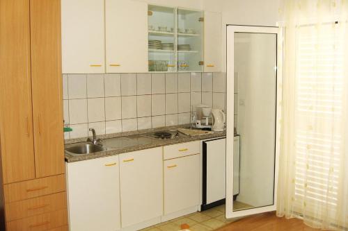 a kitchen with white cabinets and a sink at Apartments and rooms with parking space Bol, Brac - 2878 in Bol
