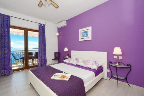 una camera da letto con pareti viola e un letto con tavolo di Apartments for families with children Seget Vranjica, Trogir - 2976 a Donji Seget