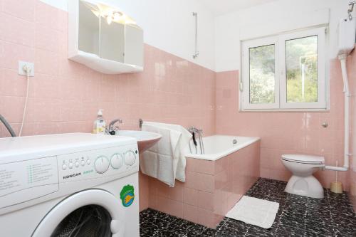 a pink bathroom with a washing machine in it at Apartments by the sea Duce, Omis - 2829 in Duće