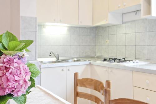 a kitchen with white cabinets and a sink and pink flowers at Apartments by the sea Razanj, Rogoznica - 2970 in Rogoznica