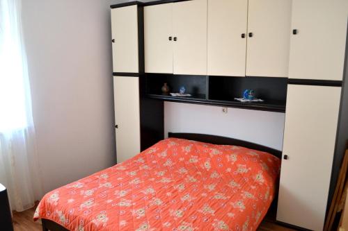 ein Schlafzimmer mit weißen Schränken und einem roten Bett in der Unterkunft Apartments with a parking space Postira, Brac - 2948 in Postira