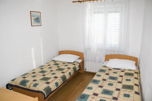 two beds in a room with white walls and a window at Apartments and rooms with parking space Bol, Brac - 2926 in Bol