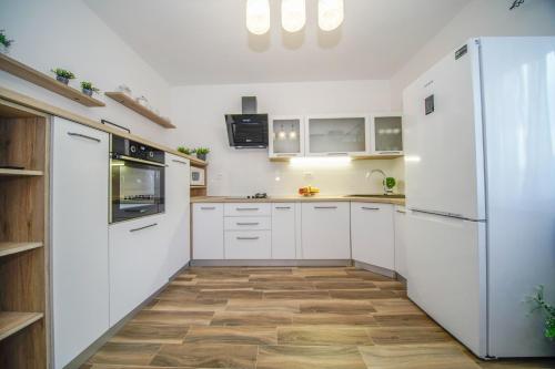 een keuken met witte apparatuur en houten vloeren bij Apartments with a parking space Splitska, Brac - 2857 in Supetar