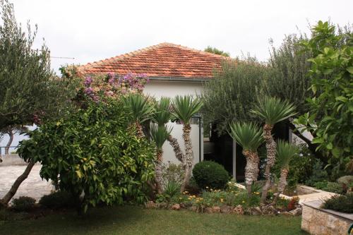 a garden in front of a house with trees and plants at Apartments by the sea Splitska, Brac - 2865 in Postira