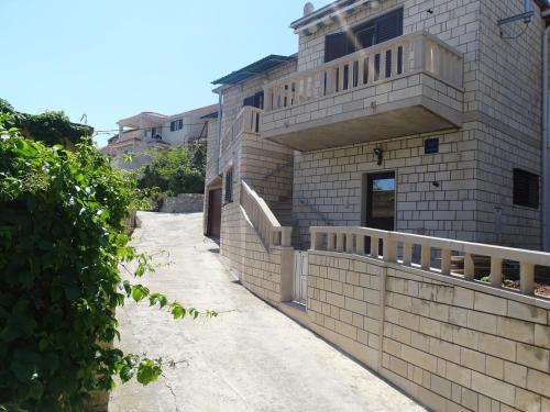 a brick building with a fence on the side of it at Apartments by the sea Sumartin, Brac - 2951 in Sumartin