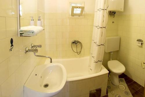 a bathroom with a sink and a tub and a toilet at Apartments by the sea Sumartin, Brac - 2951 in Sumartin