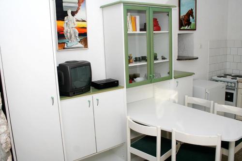 małą kuchnię z białym stołem i telewizorem w obiekcie Apartments with a parking space Bol, Brac - 2879 w Bol