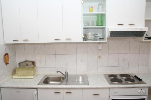 kuchnia z białymi szafkami i zlewem w obiekcie Apartment Bol 2884a w Bol