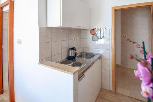 een kleine keuken met een wastafel en een aanrecht bij Apartments by the sea Duce, Omis - 2992 in Dugi Rat