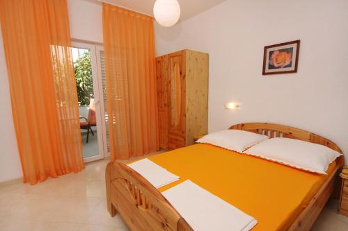 a bedroom with a wooden bed with an orange blanket at Apartments with parking space Vodice - 2995 in Vodice