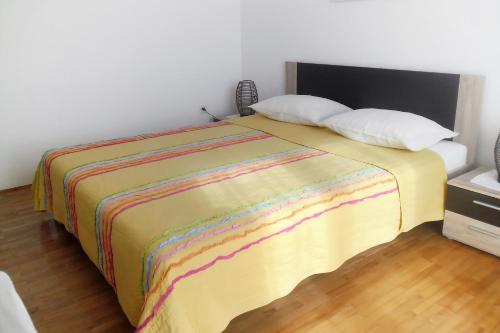 a bed with a colorful blanket and two pillows at Apartments by the sea Splitska, Brac - 2923 in Postira