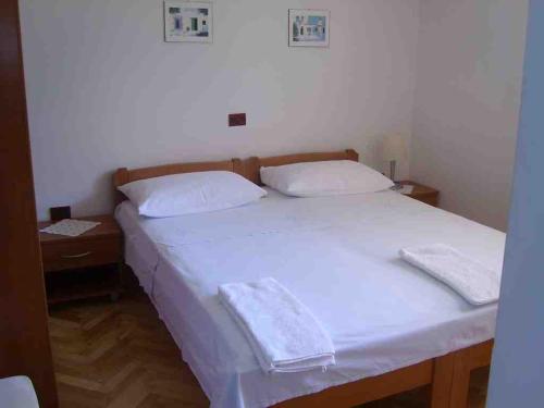 un letto bianco con due cuscini sopra di Apartments and rooms by the sea Sutivan, Brac - 2943 a Sutivan (San Giovanni di Brazza)