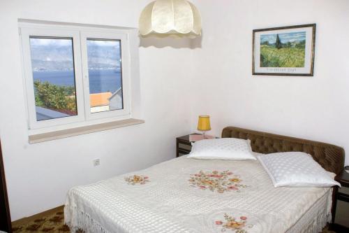 a bedroom with a bed with a window at Apartments with a parking space Splitska, Brac - 2858 in Postira