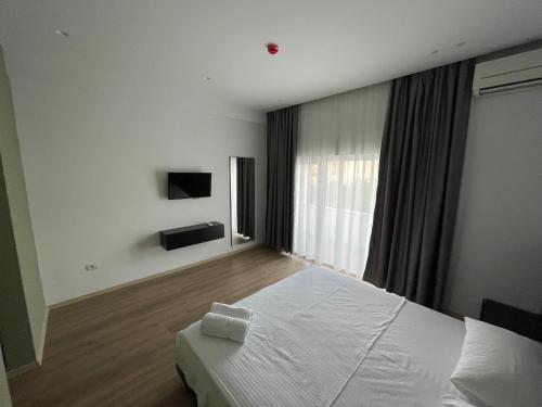 a bedroom with a white bed and a large window at Ladi Rooms in Tirana