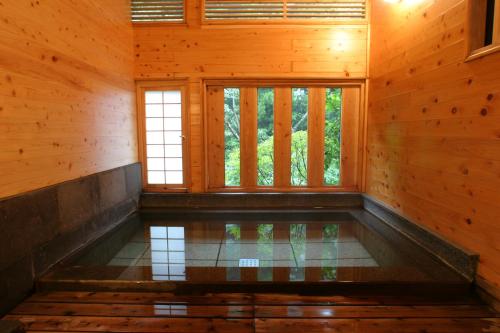 a swimming pool in a wooden room with a window at Kurokawa Onsen Oku no Yu in Minamioguni