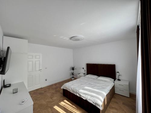 - une chambre blanche avec un lit et un bureau dans l'établissement Ancodirect Apartments, à Rădăuţi
