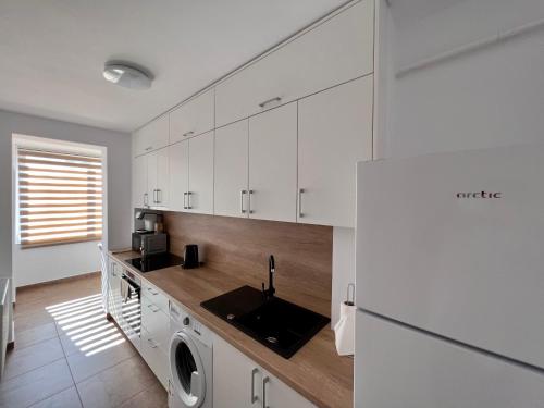 - une cuisine avec des placards blancs et un lave-linge dans l'établissement Ancodirect Apartments, à Rădăuţi