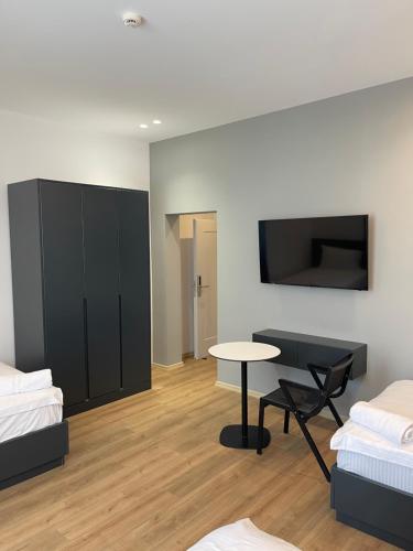 a room with two beds and a table and a tv at Ladi Rooms in Tirana
