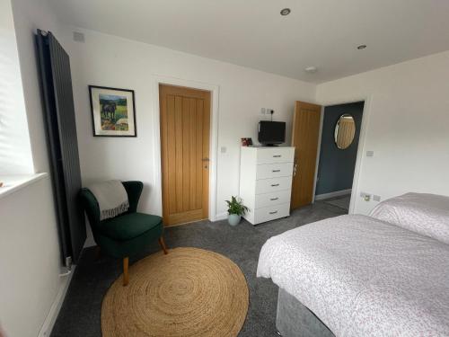a bedroom with a bed and a chair and a television at Abbey’s Inn in Cheadle