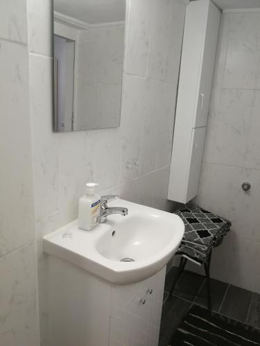 a white bathroom with a sink and a mirror at Studio Rayskata yabalka in Varna City